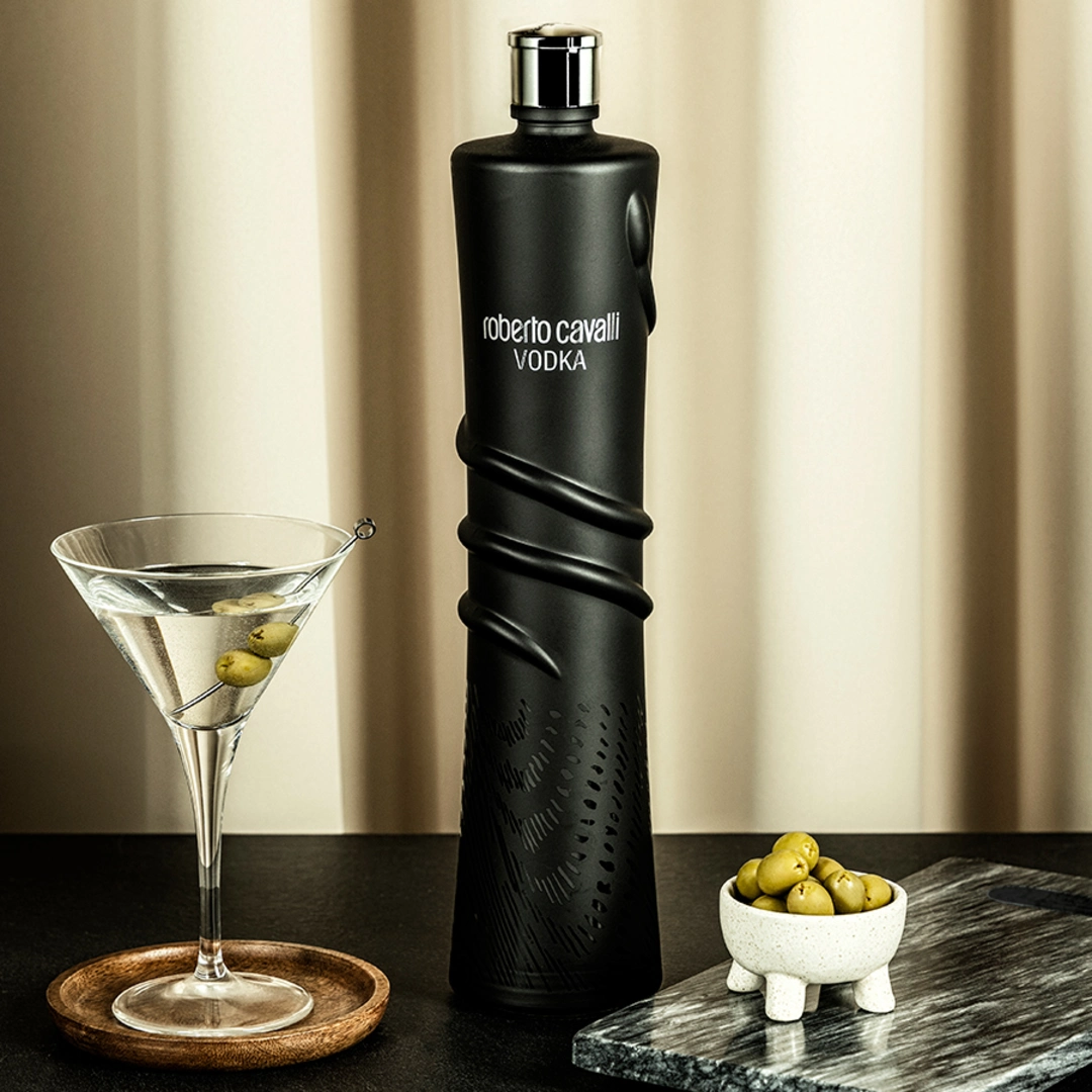 Butelka Roberto Cavalli Vodka Night Edition z martini i oliwkami na eleganckim stole