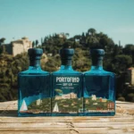 Trzy butelki ginu Portofino Dry Gin La Penisola tworzące panoramę