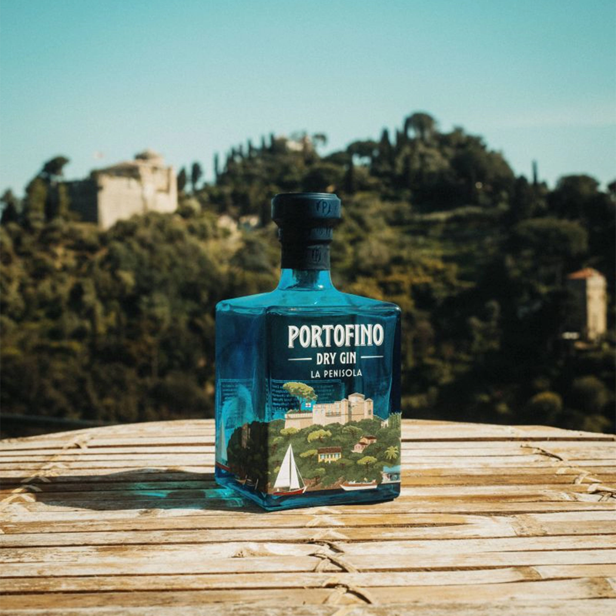 Butelka ginu Portofino Dry Gin La Penisola na tle włoskiego krajobrazu