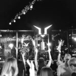 A group of people at a club party with a presenter holding a bottle of LOUERS®.