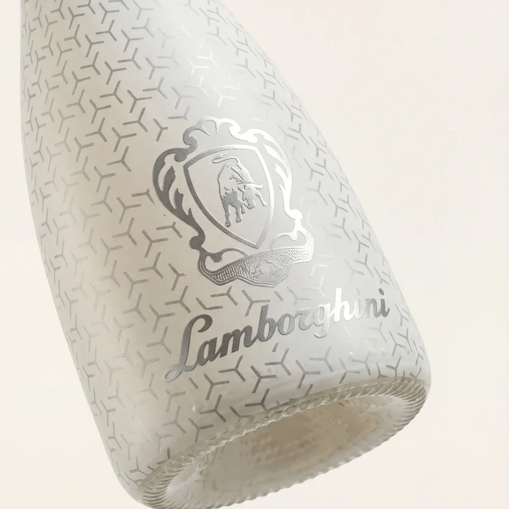 Close-up of a white bottle of Lamborghini Ice Brut wine. A delicate geometric pattern and a luxury silver Lamborghini logo are visible