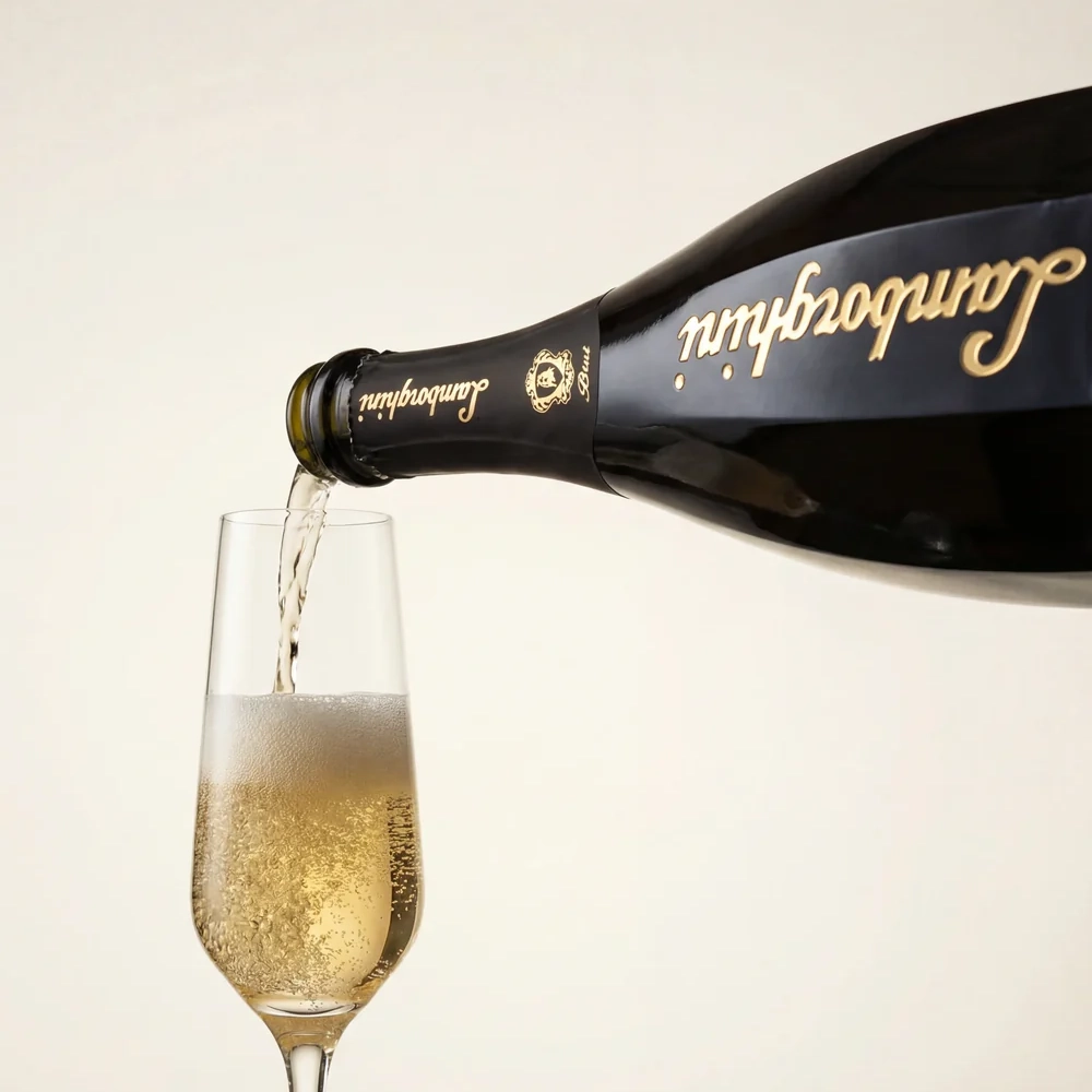 Pouring sparkling wine from a stylish black Lamborghini Ottagonale Brut Gold bottle with a gold logo into a tall, elegant flute glass against a light background. Intense bubbles are visible
