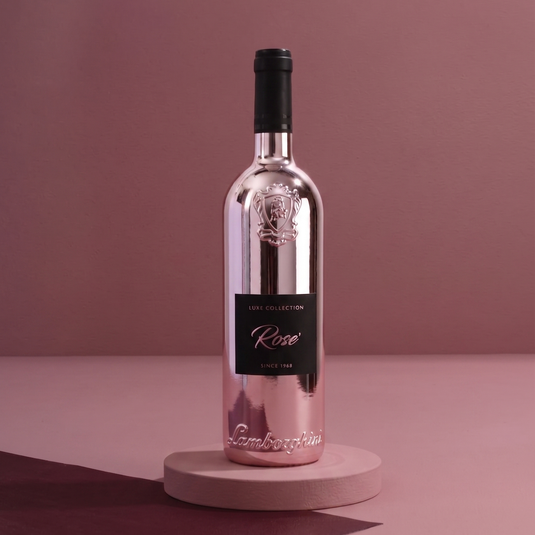 Jasnoróżowa, metaliczna butelka wina Lamborghini Luxe Rosé wyeksponowana na małym, okrągłym podeście na minimalistycznym, bordowo-różowym, studyjnym tle.