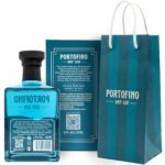 The back of a Portofino gin bottle and box showing botanical ingredients, volume, and alcohol content, next to a blue striped gift bag