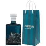 Lewy bok butelki Portofino Dry Gin Winter Nights 500 ml z ilustracją kościoła na skalistym wybrzeżu, obok torba Portofino